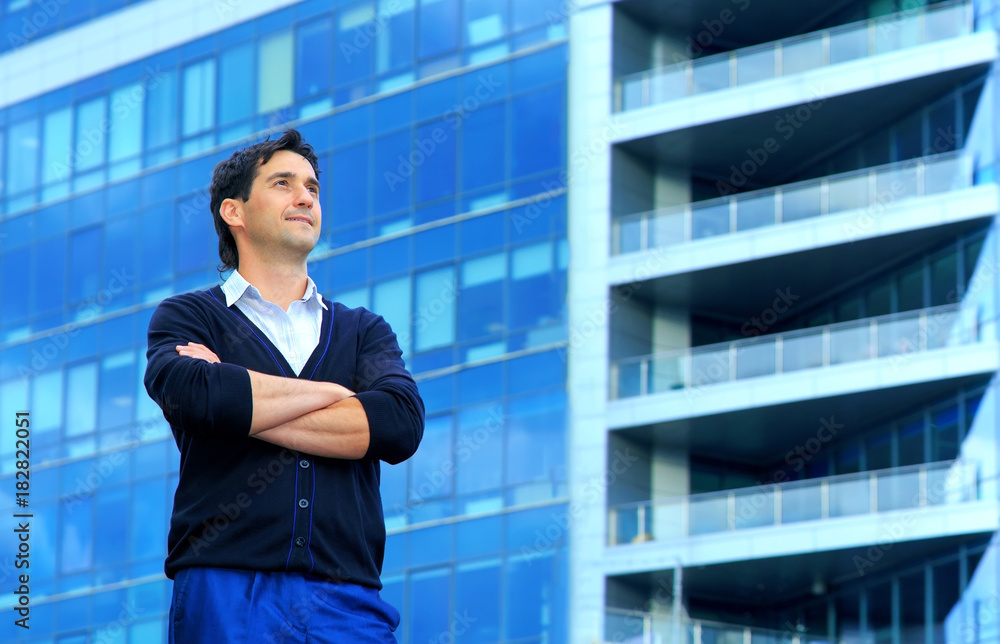 Fototapeta premium Confident happy men entrepreneur enjoying calm after hard work day. Portrait of a young successful business man thinking about something on the background of an office building.