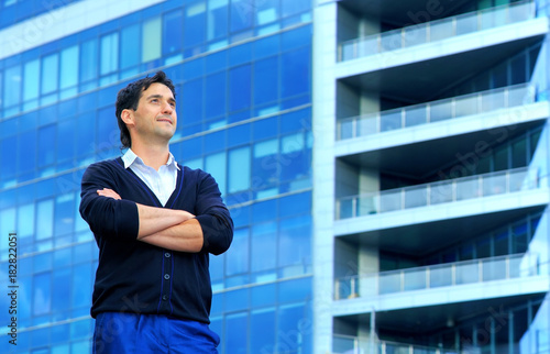 Confident happy men entrepreneur enjoying calm after hard work day. Portrait of a young successful business man thinking about something on the background of an office building.