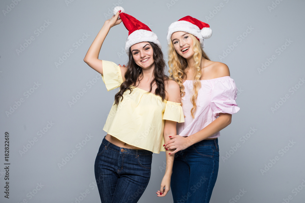 Portrait of two lovely happy women in santa hats having fun isolated over white background Portrait of two lovely happy women in santa hats having fun isolated over white background