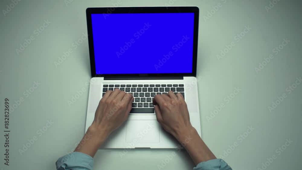 Top view male hands using laptop computer with green screen at white desk. Top view male hands using laptop computer with green screen at white desk.