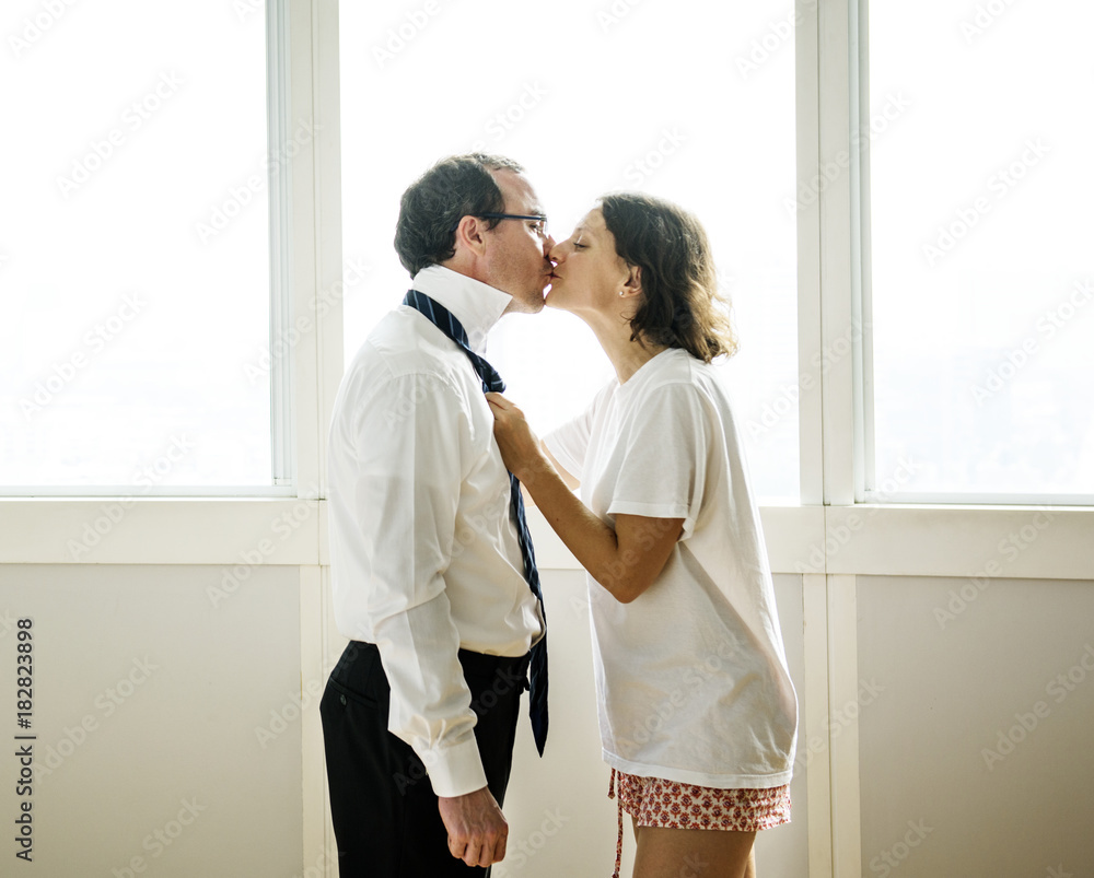 Woman kissing husband goodbye in the morning Woman kissing husband goodbye in the morning