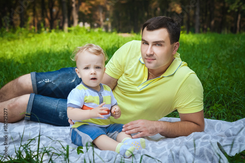 handsome guy resting with his son in forest, healthy young man playing with little son in city park © luckyphoto