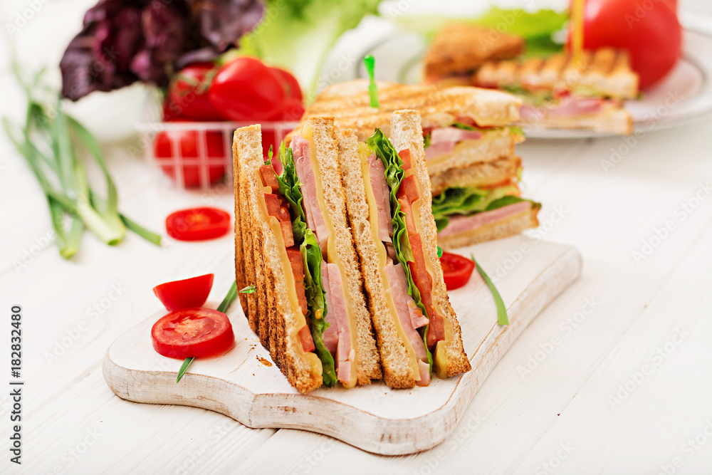 Club sandwich - panini with ham, cheese, tomato and herbs. Top view Club sandwich - panini with ham, cheese, tomato and herbs. Top view