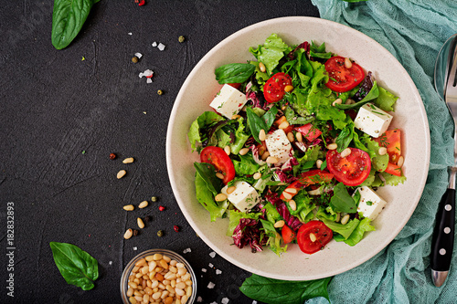 Dietary salad with tomatoes, feta, lettuce, spinach and pine nuts. Top view. Flat lay.
