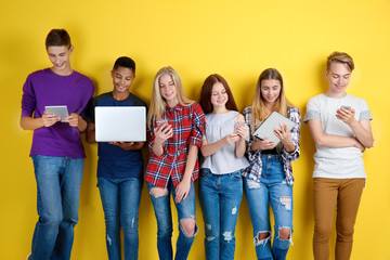 Cute teenagers with modern gadgets on color background