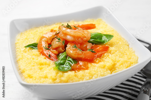 Bowl with fresh tasty shrimp and grits on table, closeup
