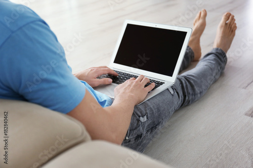 Man using laptop while sitting on floor indoors