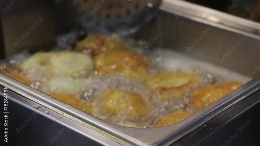Deep frying - cooking fried cakes in oil. Closeup. Selective focus. Deep frying - cooking fried cakes in oil. Closeup. Selective focus.