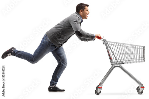Guy running and pushing an empty shopping cart isolated on white background
