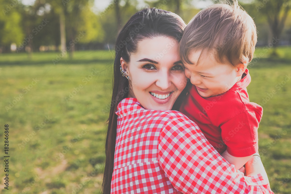 happy mum with kid smiling in the park. hipster style. casual clothes. concept of happy family happy mum with kid smiling in the park. hipster style. casual clothes. concept of happy family