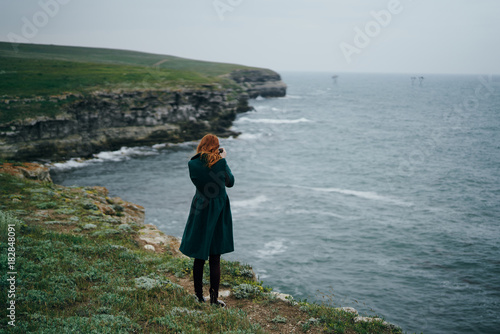 Beautiful young woman in the nature, standing on a cliff
