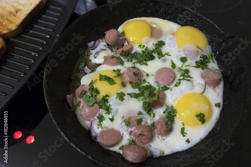 cooking fried eggs with sausages