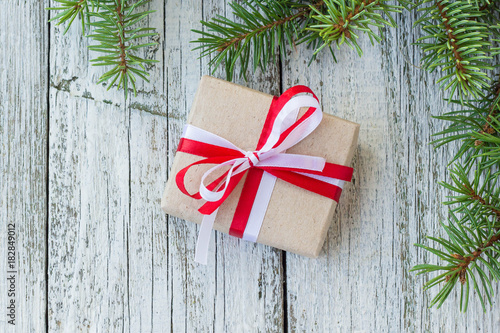 Christmas gift boxes with red and white ribbon on wooden background with Fir branches.