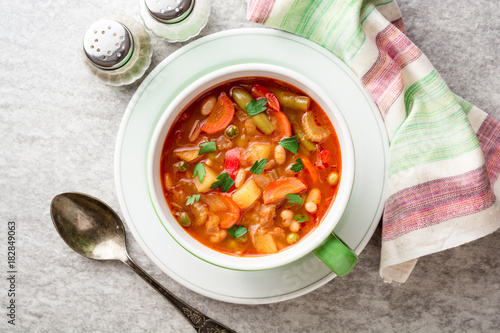 Italian minestrone soup in bowl on gray stone background