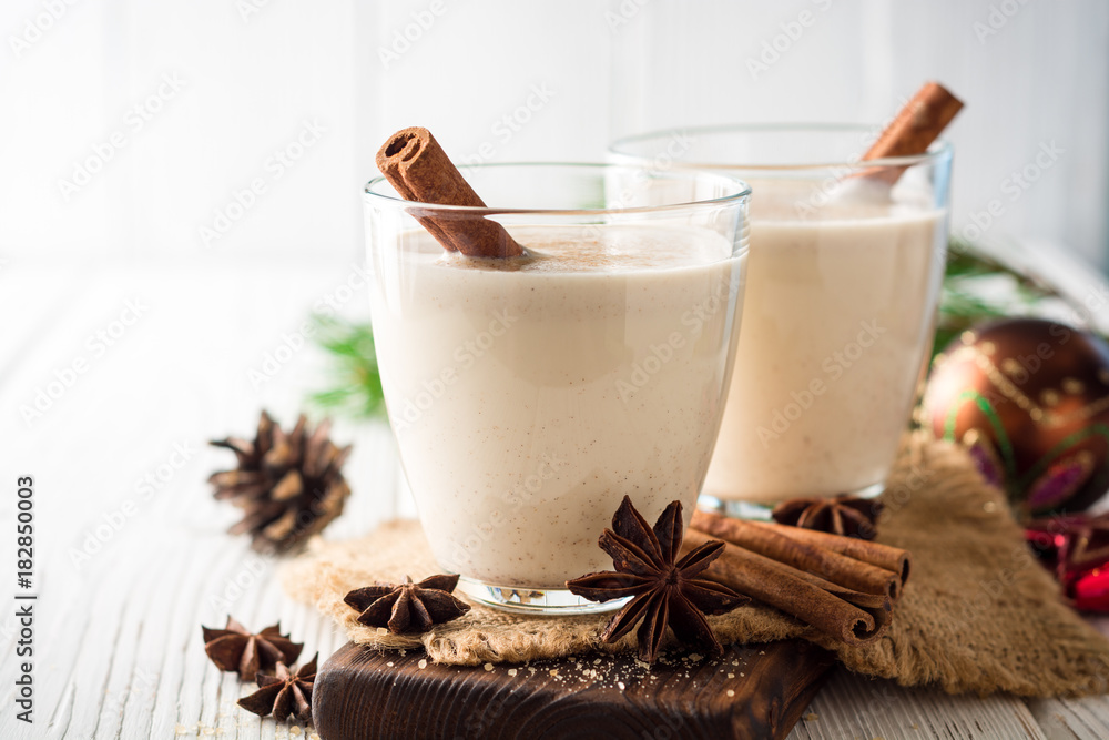 Homemade eggnog with grated nutmeg and cinnamon on white wooden table. Traditional Christmas drink. Homemade eggnog with grated nutmeg and cinnamon on white wooden table. Traditional Christmas drink.