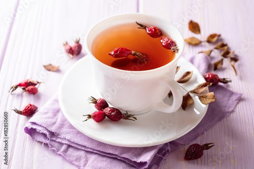 Cup of herbal tea from rose hips on purple wooden background