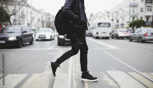 Modern young bearded man in black style clothes is walking at street. photo