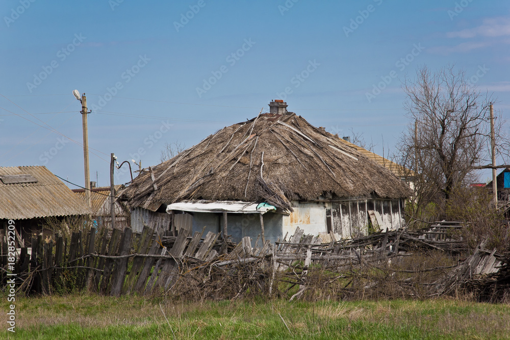 Abandoned Russian village. Ruins of rural house with thatched roof