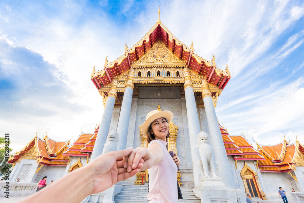 Naklejka premium Asian tourist women in hat leading man hand to travel at marble temple