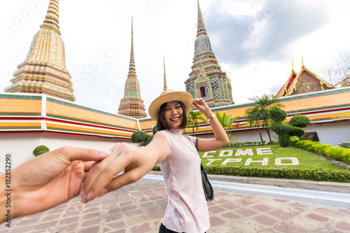 Tourist women with hat leading man to travel in Wat Pho temple