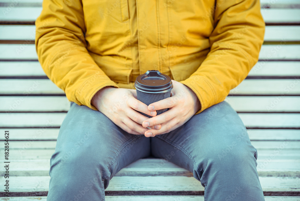 man waiting on the bench of city park with cup of coffe man waiting on the bench of city park with cup of coffe