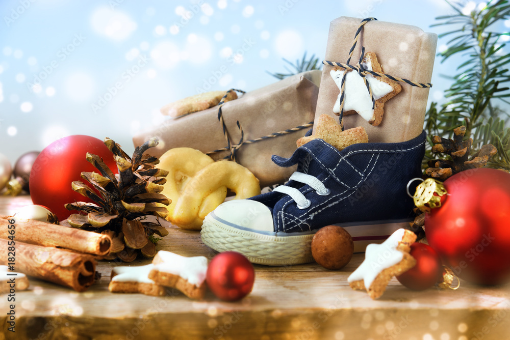 St. Nicholas Day, Children's shoe with sweets, gifts and christmas  ornaments on rustic wood, light blue snowy background, in Germany called  Nikolaus Stock Photo | Adobe Stock