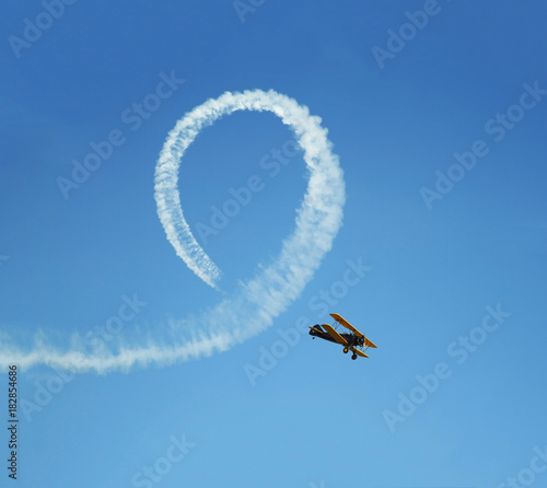 Fotografie Vintage biplane does loop stunt with smoke trails