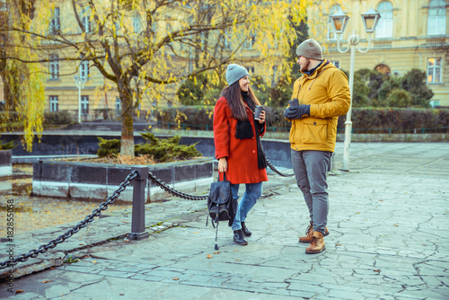 man flirting with woman while walking the park with cup of coffee