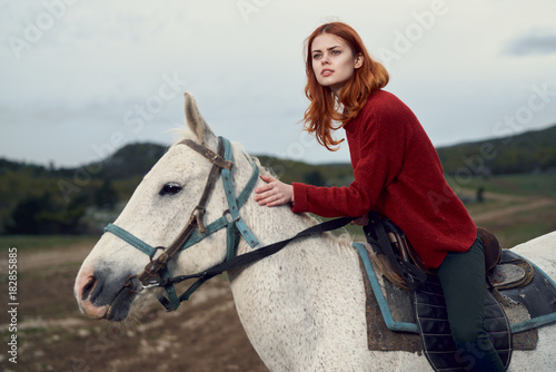 Beautiful young woman in the mountains walking with her horse