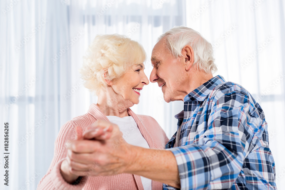 side view of smiling senior couple dancing together at home side view of smiling senior couple dancing together at home