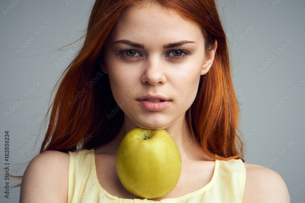 Beautiful young woman on a gray background holding an apple Beautiful young woman on a gray background holding an apple