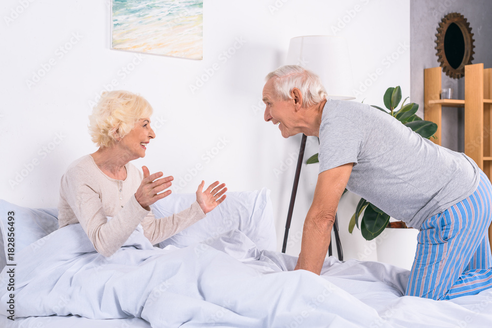 side view of happy senior wife and husband resting in bed at home side view of happy senior wife and husband resting in bed at home