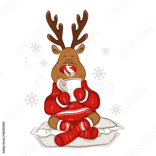  Christmas reindeer sits on a pillow. It's holds a mug with hot tea in his hands. From the mug there is steam. It's is wearing a warm knitted sweater and socks with ornament. Isolated. 