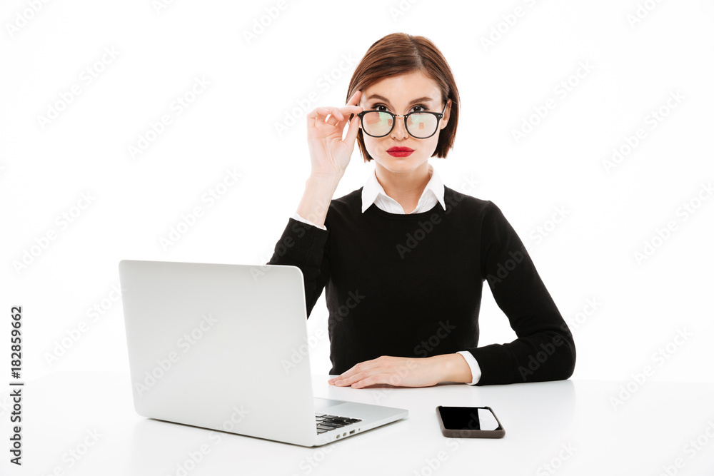 Serious young business lady wearing glasses using laptop Serious young business lady wearing glasses using laptop
