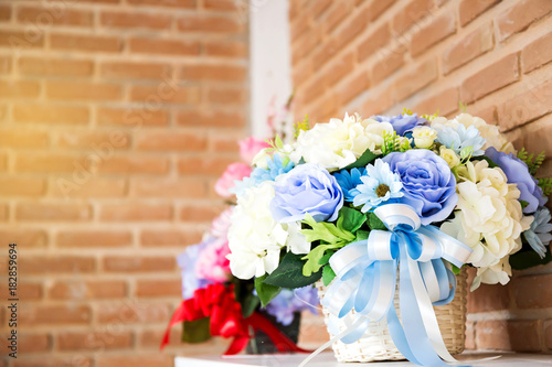 Artificial flower in the pot over wood table , brick wall background