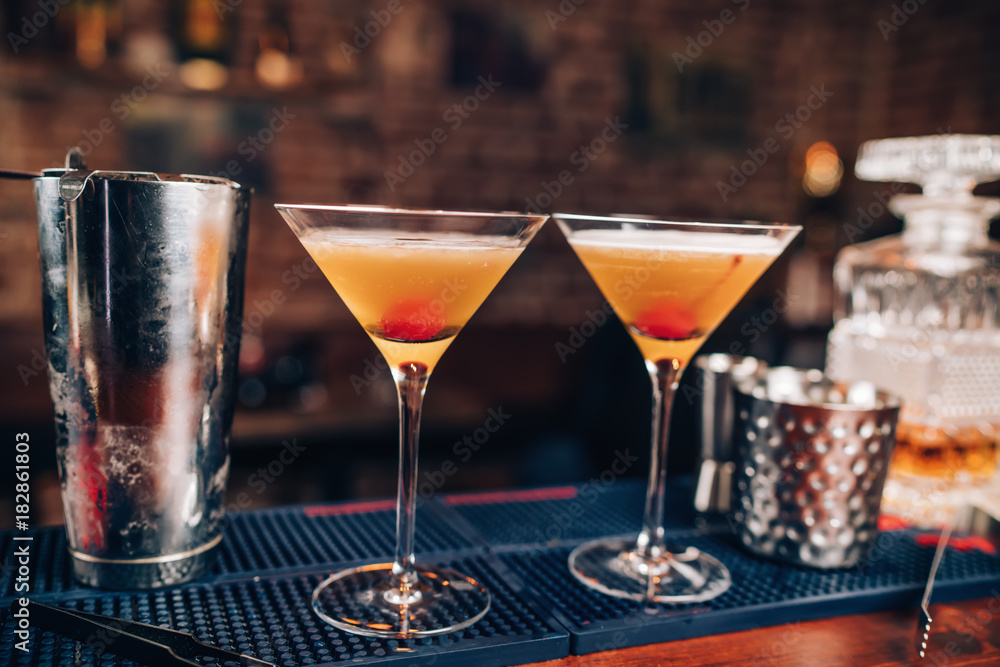 Two fresh alcoholic cocktails on bar counter. Close up of bar details with beverages and drinks Two fresh alcoholic cocktails on bar counter. Close up of bar details with beverages and drinks