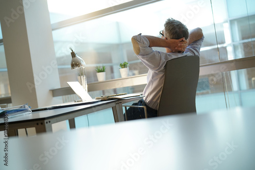 Businessman in office relaxing in desk chair photo