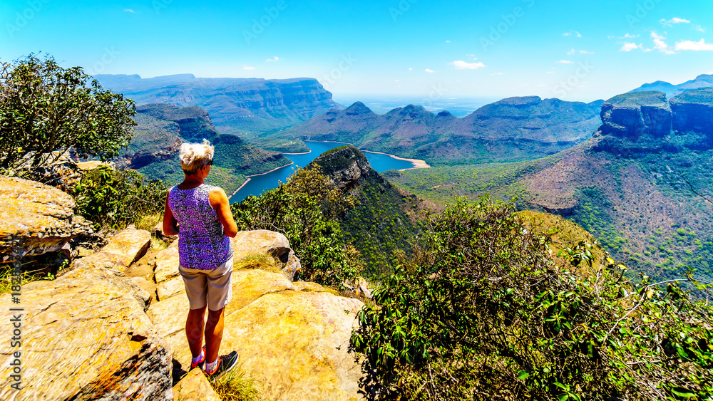 Senior woman enjoying the view of the Blyde River Canyon and Blyde River Dam from the viewpoint at the Three Rondavels along the Panorama Route in Mpumalanga Province of South Africa