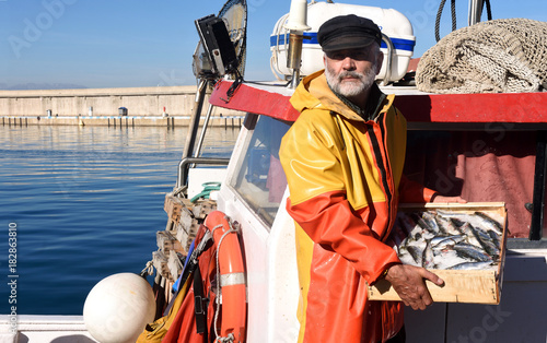 Fényképezés fisherman with a fish box inside a fishing boat
