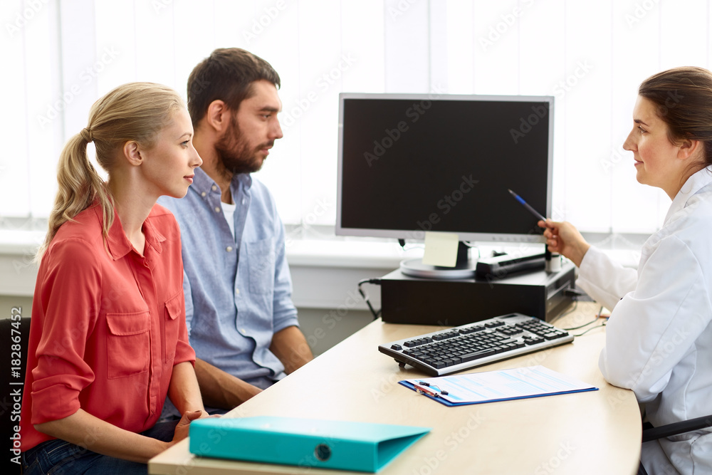couple and doctor pointing at computer at clinic couple and doctor pointing at computer at clinic