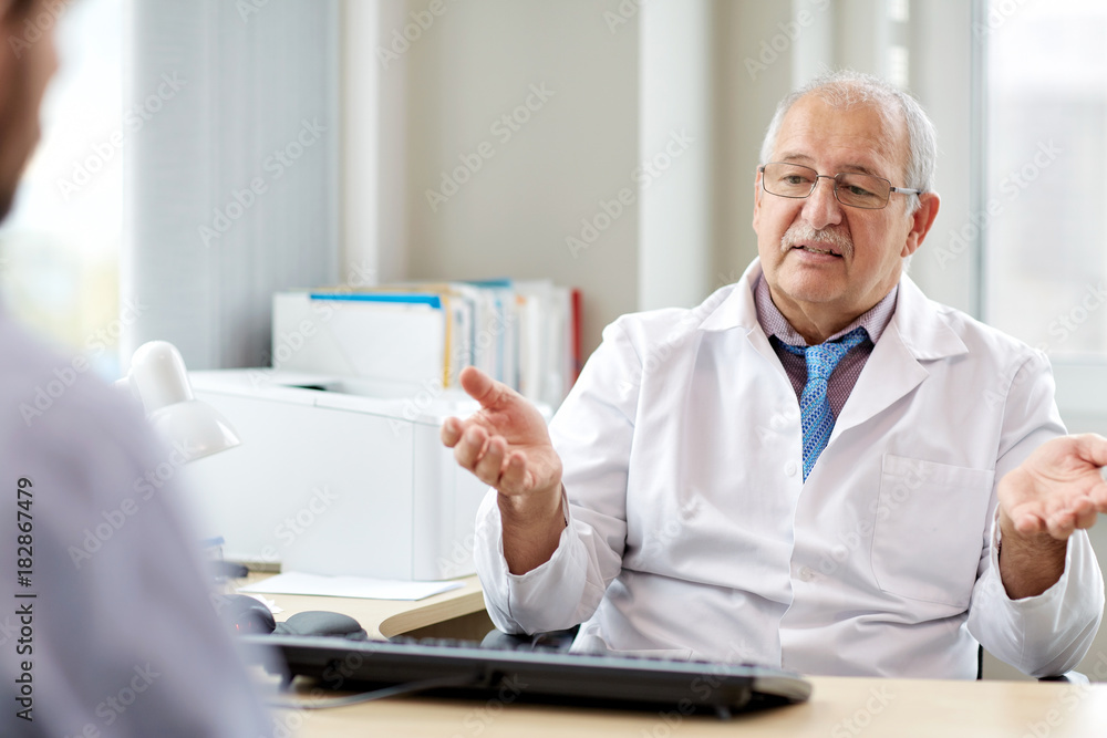 senior doctor talking to male patient at hospital