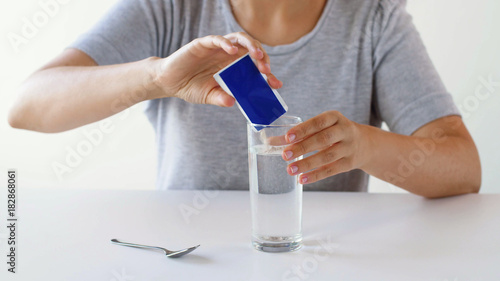 woman pouring medication into glass of water