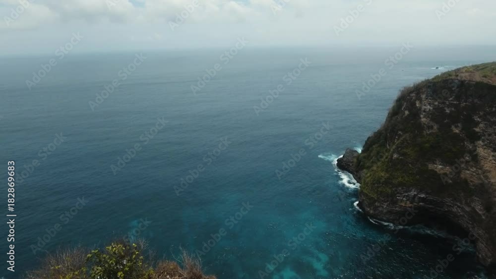 Aerial view of young girl stands on the edge of a cliff and looks at the sea. Girl raising her hands up on the edge of the cliff enjoys the view of the ocean. 4K video. Travel concept. Aerial footage. Aerial view of young girl stands on the edge of a cliff and looks at the sea. Girl raising her hands up on the edge of the cliff enjoys the view of the ocean. 4K video. Travel concept. Aerial footage.
