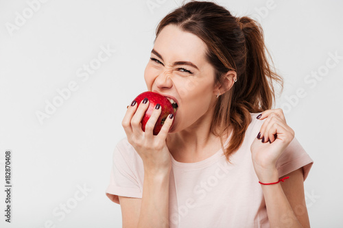Obraz na plátně Close up portrait of a hungry pretty girl biting an apple