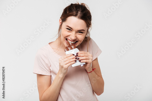 Portrait of a hungry pretty girl biting chocolate bar
