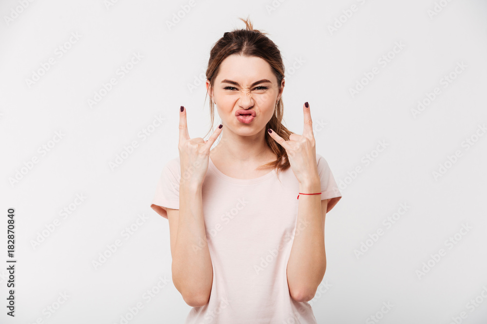 Portrait of a funny girl showing rock gesture with fingers Portrait of a funny girl showing rock gesture with fingers