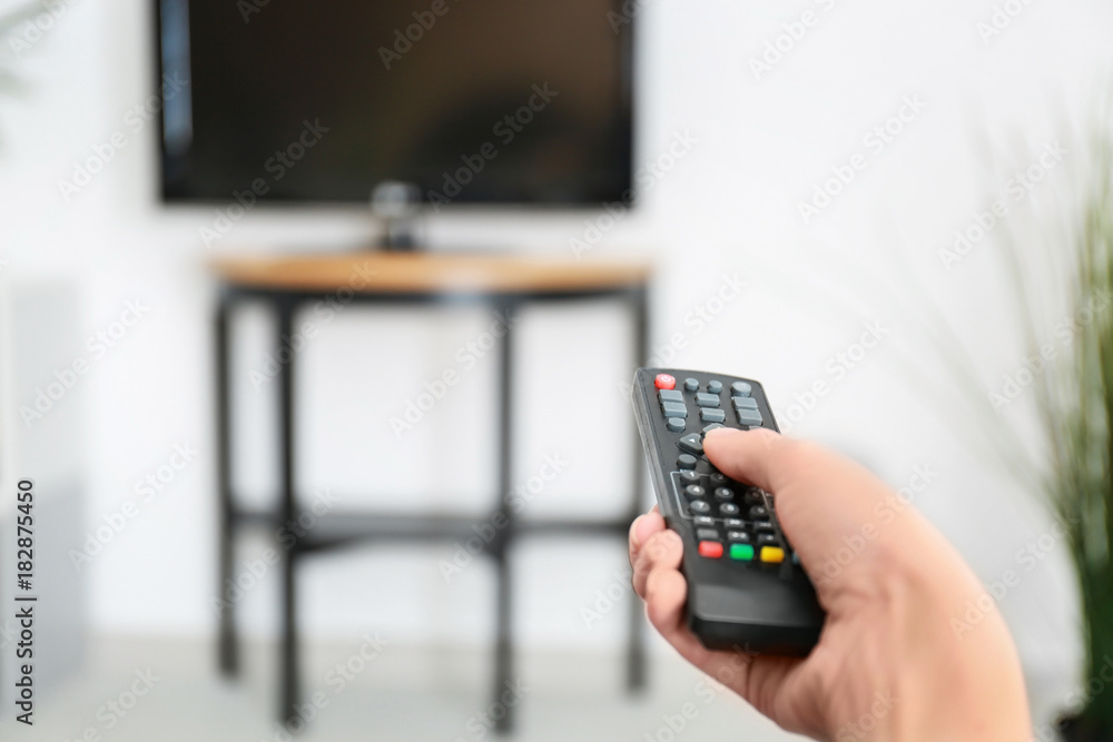 Woman with TV remote control switching channels, closeup Woman with TV remote control switching channels, closeup