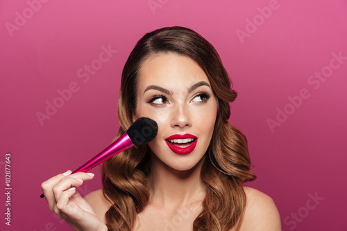 Pretty caucasian lady with make up brush looking aside
