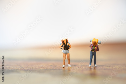 Travel Concept. Two female traveller miniature figure with backpck standing on map.