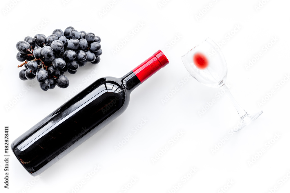 Taste red wine. Bottle of red wine, glass and black grape on white background top view copyspace Taste red wine. Bottle of red wine, glass and black grape on white background top view copyspace